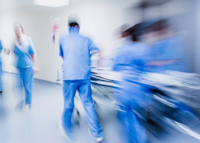 Stylized shot with blur of nurses wheeling patient down a hallway.