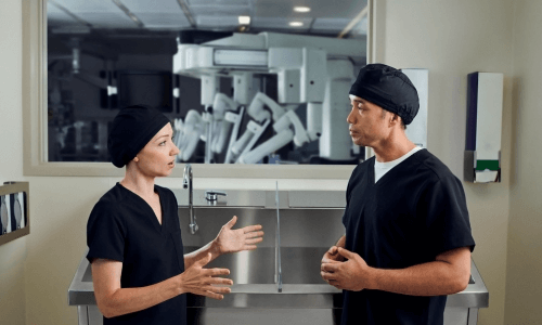 July Intuitive Webinar Image 500x300 Nurse talking with a teammate in front of an operating room.