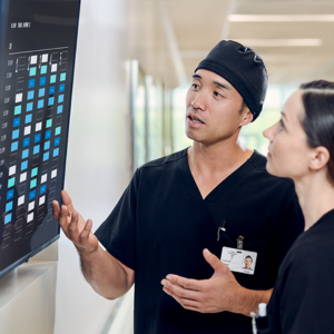 two healthcare workers in scrubs looking at monitor