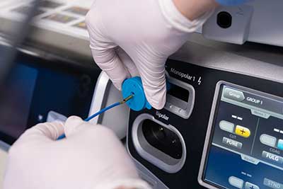 A nurse plugs in a foot pedal adaptor to an electrosurgery machine