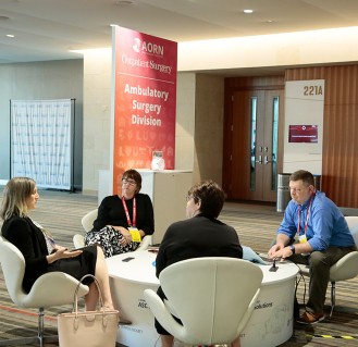ASC-Ambulatory-Hub-Expo-329x319 Group of people sit around small table in conference room at Expo.