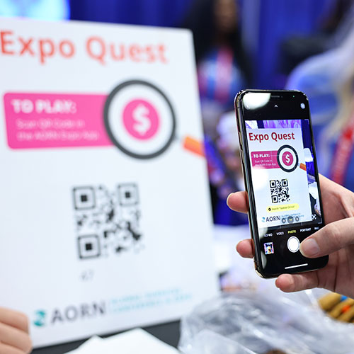 Expo-Quest-500x500 Person uses phone to scan QR code on Expo Quest sign.