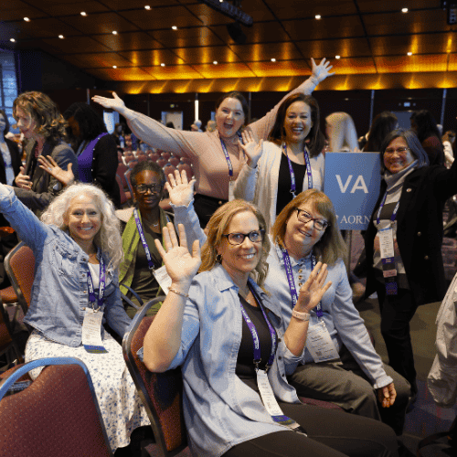 A formal conference setting with happy participants seated and standing up.