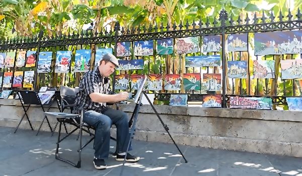 Artist painting outdoors near a fence