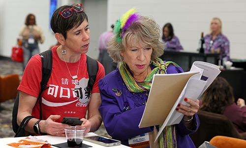 Two people at a table look at a document.