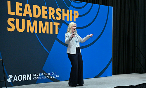 A woman stands in front of a Leadership Summit sign.